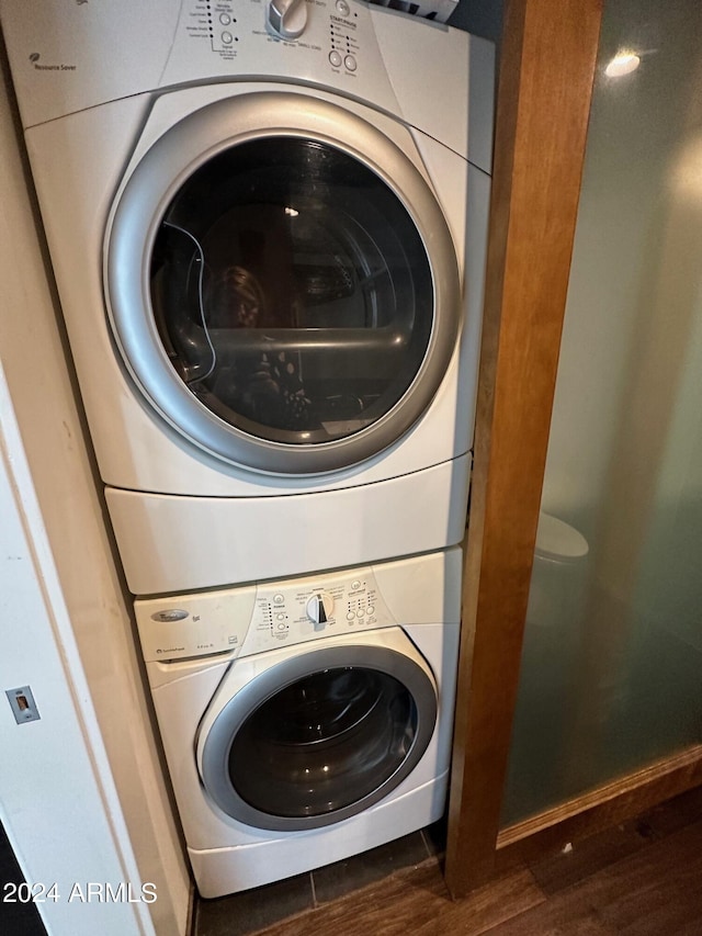 clothes washing area with dark hardwood / wood-style floors and stacked washer and clothes dryer