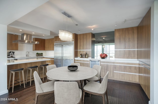 dining space with track lighting, dark wood-type flooring, sink, an inviting chandelier, and wine cooler