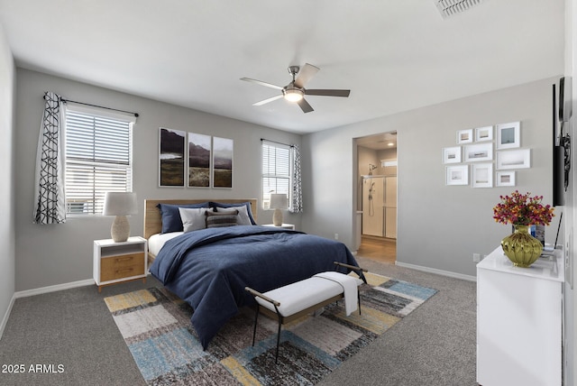 bedroom with ceiling fan, ensuite bathroom, and dark carpet