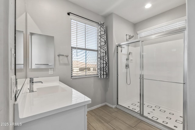 bathroom featuring a shower with door and vanity