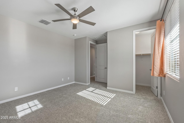 unfurnished bedroom with a spacious closet, light carpet, ceiling fan, a closet, and multiple windows