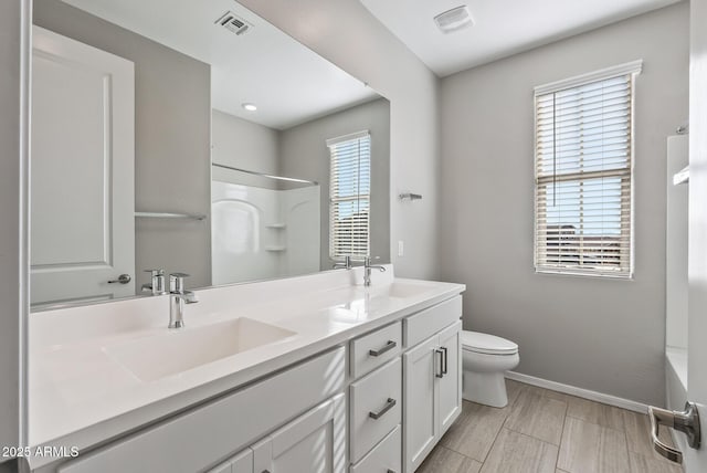 bathroom with toilet, vanity, and a healthy amount of sunlight