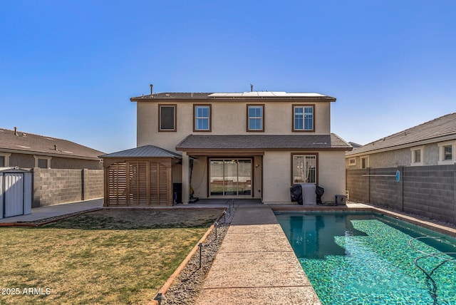 back of house with a yard, a fenced in pool, and solar panels