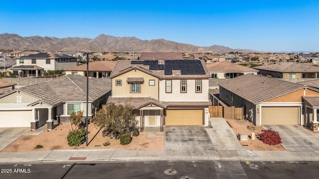 view of front of house with a garage, a mountain view, and solar panels