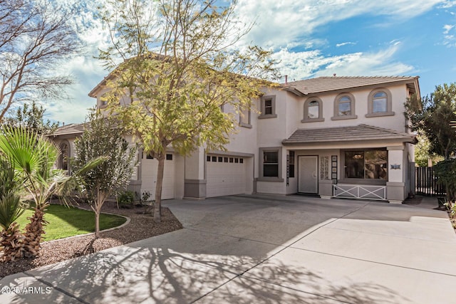 view of front facade featuring a garage, fence, concrete driveway, a tiled roof, and stucco siding