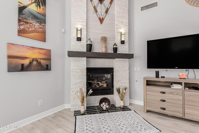 337 E Clairidge Dr, San Tan Valley, AZ 85143 - living room with a large fireplace, light wood finished floors, visible vents, and baseboards