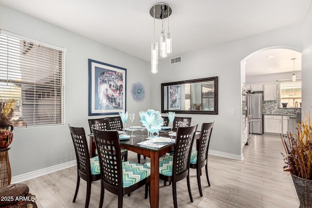 337 E Clairidge Dr, San Tan Valley, AZ 85143 - dining space with light wood-style floors, arched walkways, visible vents, and baseboards