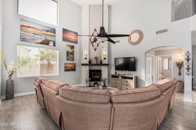 337 E Clairidge Dr, San Tan Valley, AZ 85143 - living room with visible vents, arched walkways, a ceiling fan, a high ceiling, and light wood-style floors