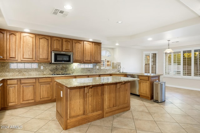 kitchen with a center island, stainless steel appliances, light stone counters, backsplash, and pendant lighting