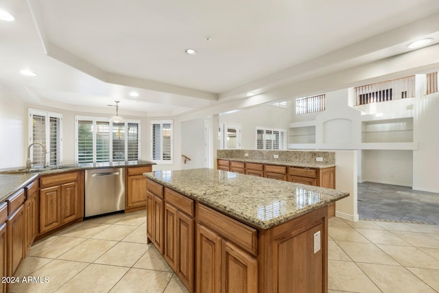 kitchen with light stone countertops, stainless steel dishwasher, sink, decorative light fixtures, and a center island