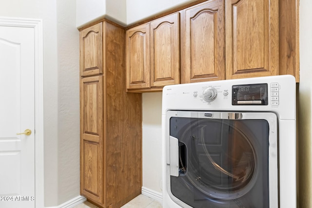 clothes washing area featuring cabinets, light tile patterned floors, and washer / clothes dryer