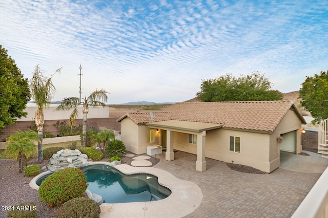 rear view of property featuring a fenced in pool and a patio