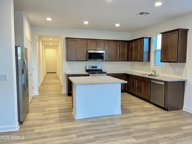 kitchen featuring dark brown cabinets, appliances with stainless steel finishes, a sink, light wood-style floors, and visible vents