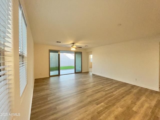spare room featuring a ceiling fan, baseboards, visible vents, and wood finished floors