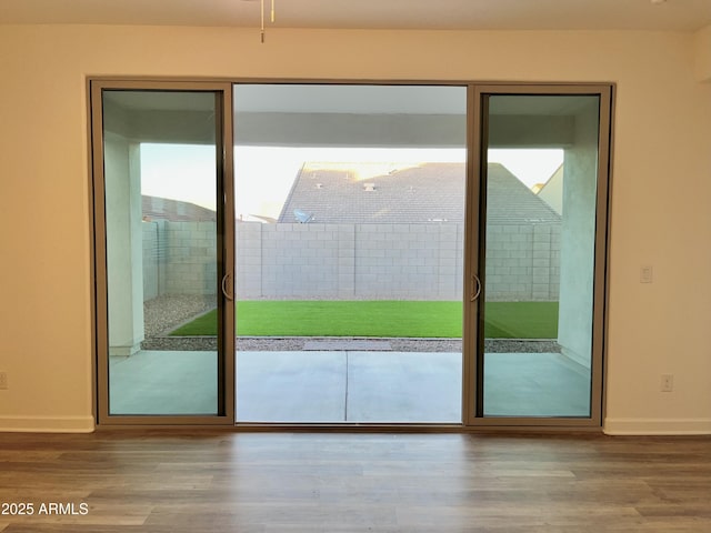 doorway with baseboards and wood finished floors