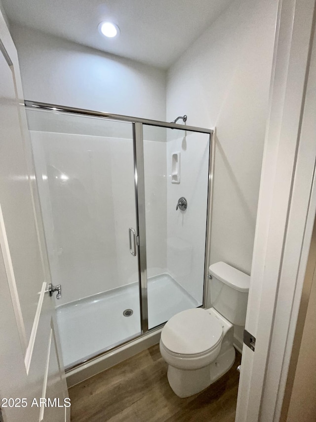 bathroom with recessed lighting, a stall shower, toilet, and wood finished floors