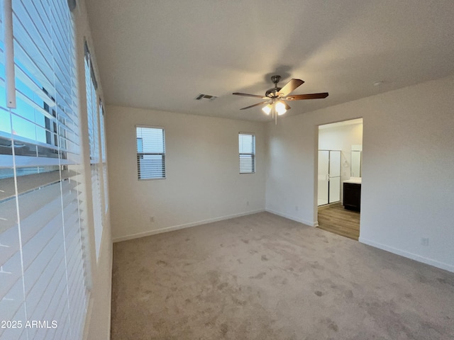 empty room with visible vents, a ceiling fan, baseboards, and light carpet