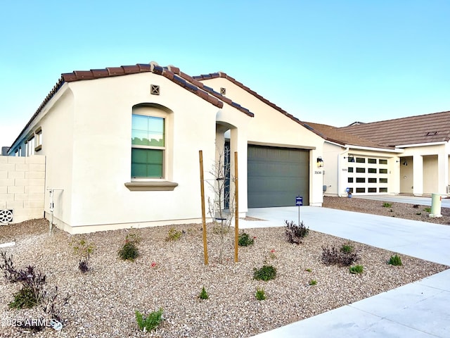 mediterranean / spanish home with fence, stucco siding, a tiled roof, an attached garage, and driveway