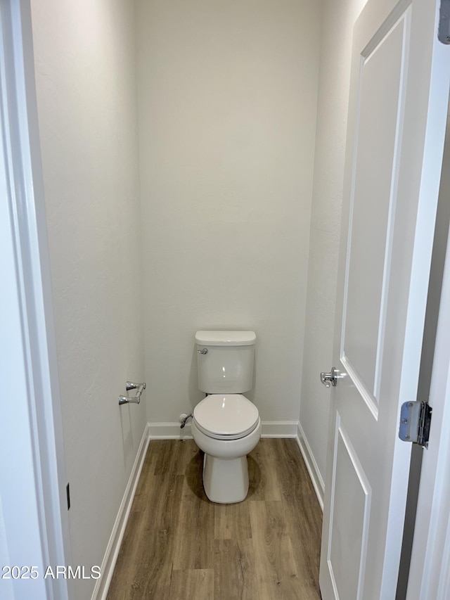 bathroom featuring baseboards, toilet, and wood finished floors