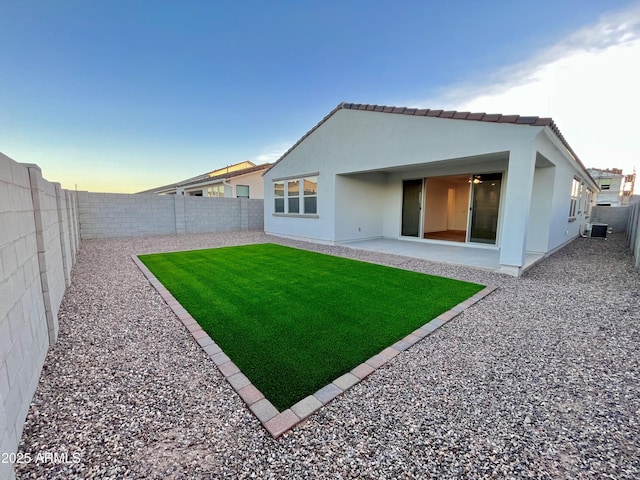 back of house with a fenced backyard, stucco siding, a yard, and central AC unit