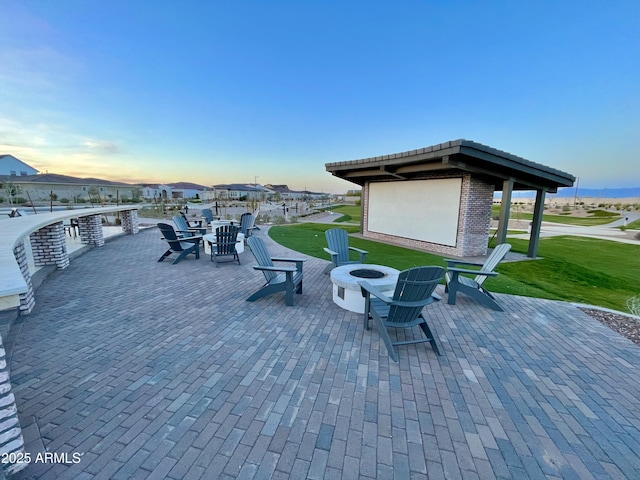patio terrace at dusk featuring a lawn and an outdoor fire pit