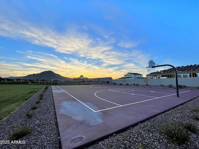view of basketball court featuring fence, community basketball court, a mountain view, and a yard