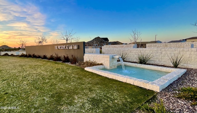 pool at dusk with a yard and fence