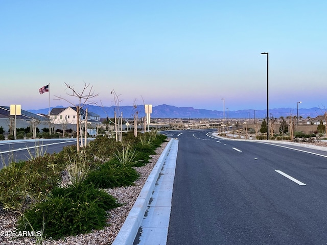view of road with street lights, a mountain view, and curbs