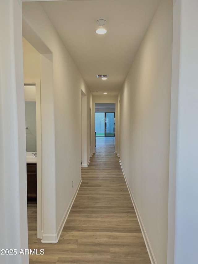 hall featuring baseboards and light wood finished floors