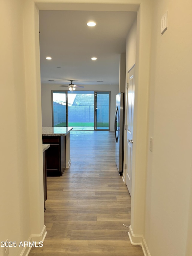 hallway featuring recessed lighting, baseboards, and light wood-style floors