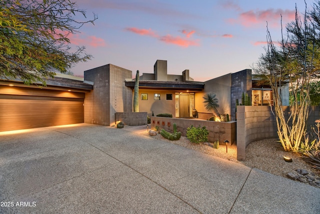 contemporary home featuring a gate, an attached garage, stucco siding, concrete driveway, and a fenced front yard