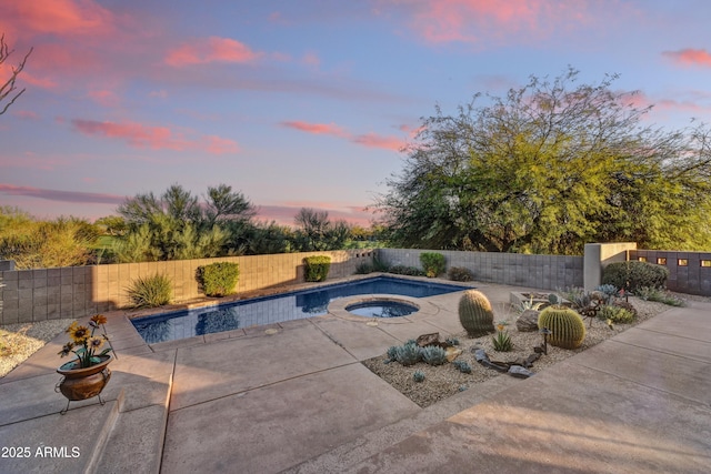 pool at dusk featuring an in ground hot tub, a fenced in pool, a fenced backyard, and a patio area