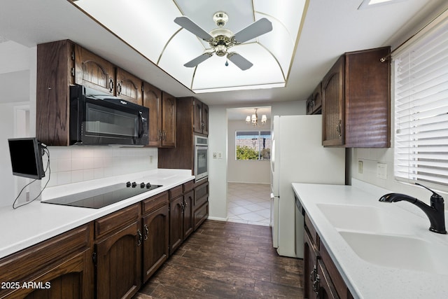 kitchen featuring sink, dark hardwood / wood-style flooring, ceiling fan with notable chandelier, decorative backsplash, and black appliances