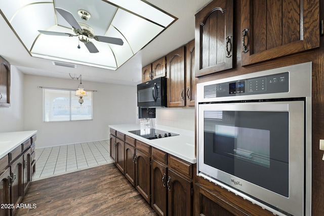 kitchen with dark wood-type flooring, ceiling fan, backsplash, hanging light fixtures, and black appliances