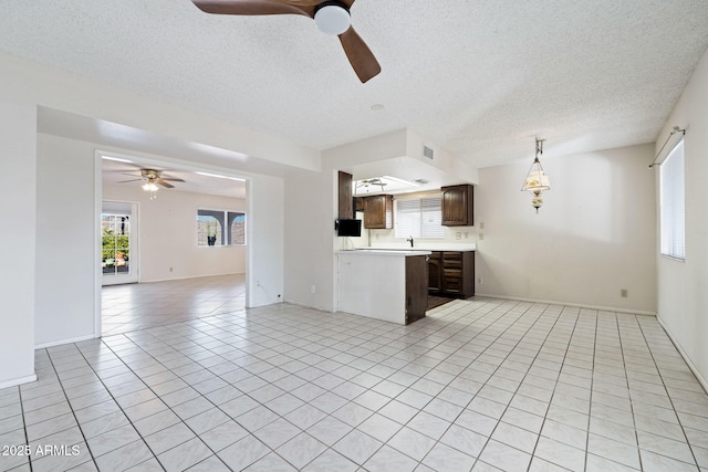 kitchen with a healthy amount of sunlight, light tile patterned floors, a textured ceiling, and dark brown cabinetry