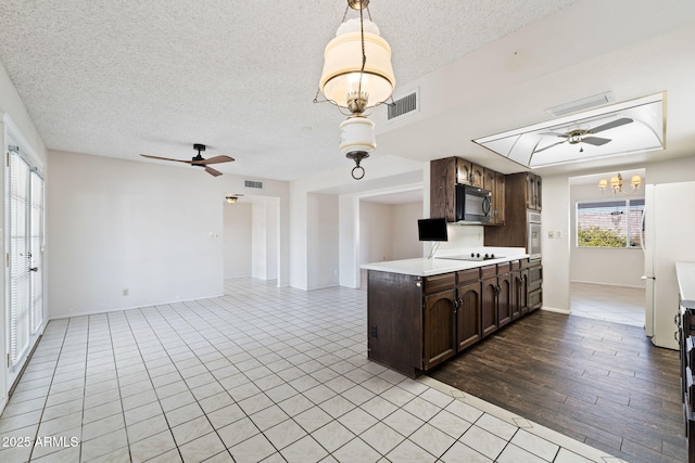 kitchen with a textured ceiling, ceiling fan with notable chandelier, dark brown cabinets, and black appliances