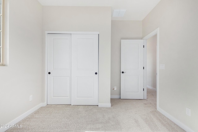 unfurnished bedroom featuring a closet and light colored carpet