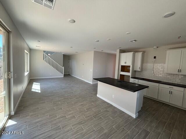 kitchen featuring backsplash, a center island, white cabinets, and hardwood / wood-style flooring