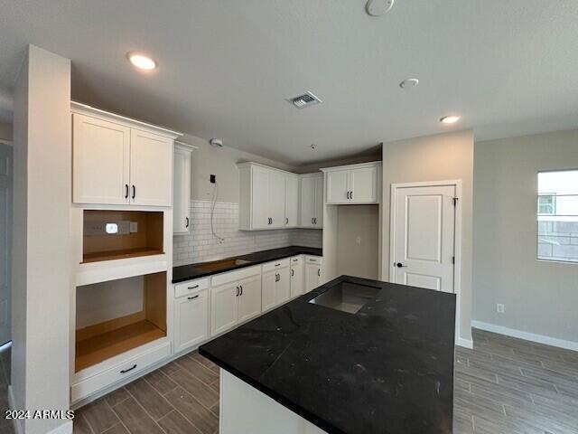 kitchen featuring decorative backsplash, a kitchen island, wood-type flooring, and white cabinetry