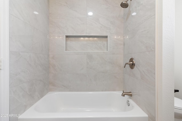 bathroom with tiled shower / bath combo and toilet