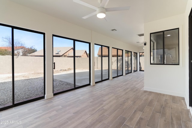 unfurnished sunroom with ceiling fan and a healthy amount of sunlight