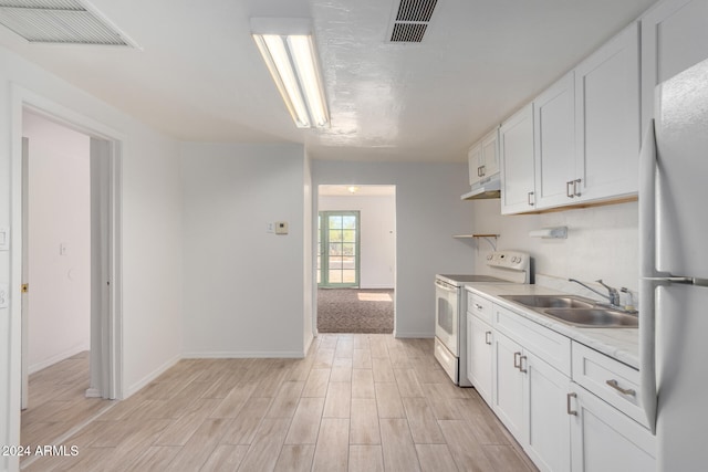 kitchen with white cabinetry, sink, light hardwood / wood-style floors, and white appliances