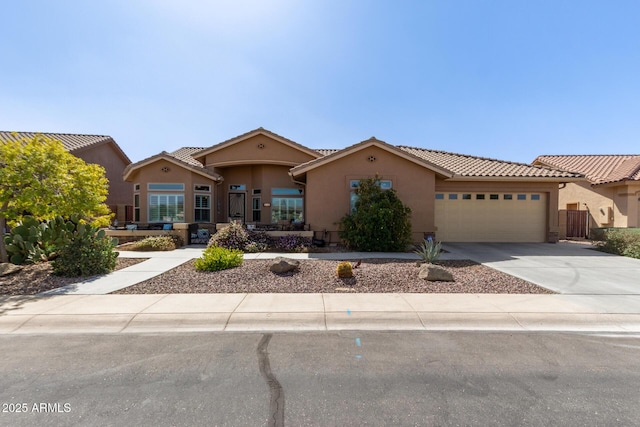 mediterranean / spanish home with a garage, a tiled roof, concrete driveway, and stucco siding