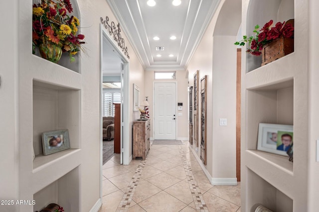 hallway featuring recessed lighting, a raised ceiling, visible vents, ornamental molding, and baseboards