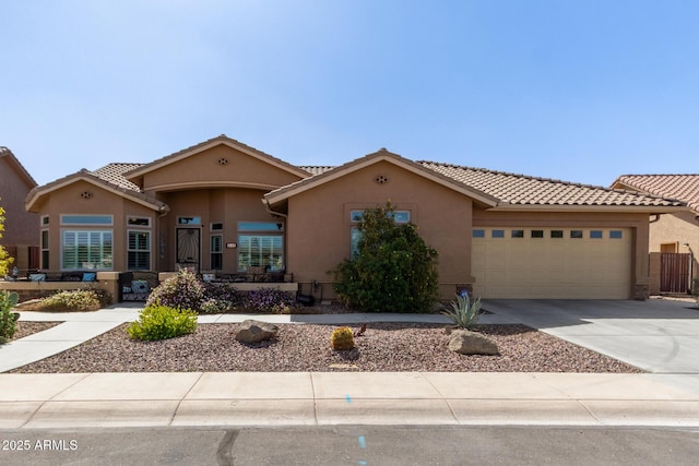 mediterranean / spanish house featuring an attached garage, a tiled roof, concrete driveway, and stucco siding