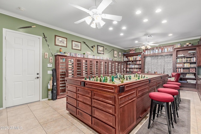 interior space featuring light tile patterned floors, a bar, a ceiling fan, and crown molding