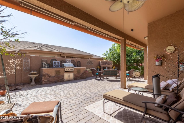 view of patio with fence, exterior fireplace, area for grilling, and ceiling fan