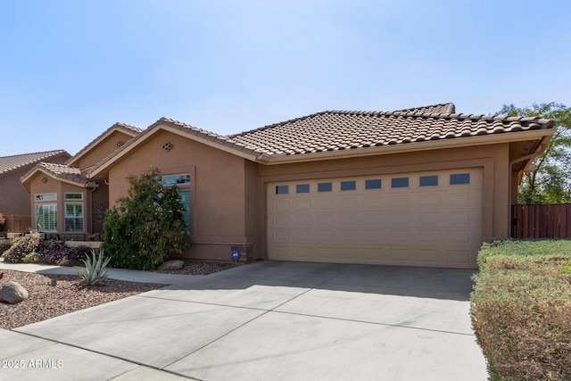 view of front facade with concrete driveway, a tile roof, an attached garage, fence, and stucco siding