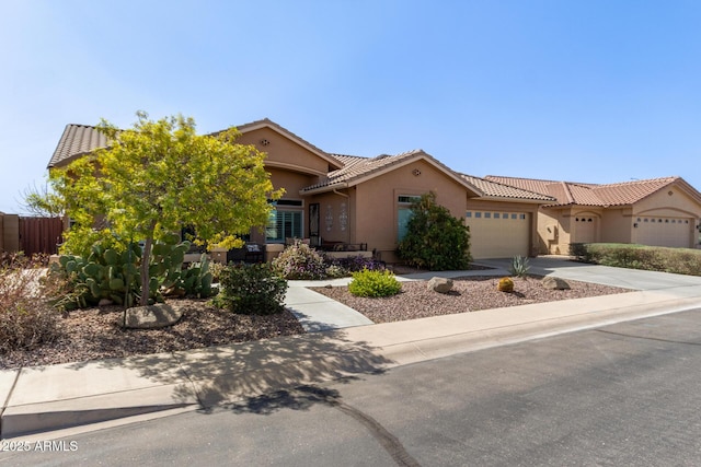 view of front of home with a garage, driveway, a tiled roof, and stucco siding