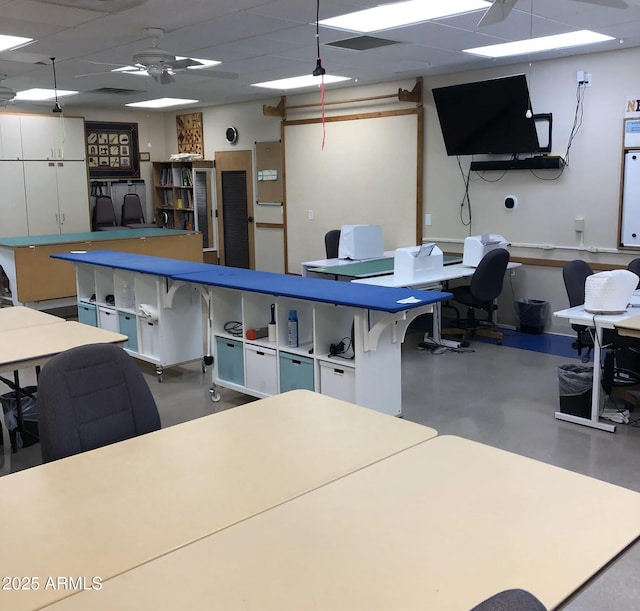 office space with ceiling fan, concrete floors, and a drop ceiling